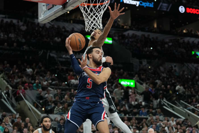 Jan 29, 2024; San Antonio, Texas, USA; Washington Wizards guard Tyus Jones (5) looks to pass under the arm of San Antonio Spurs center Victor Wembanyama (1) in the second half at Frost Bank Center.